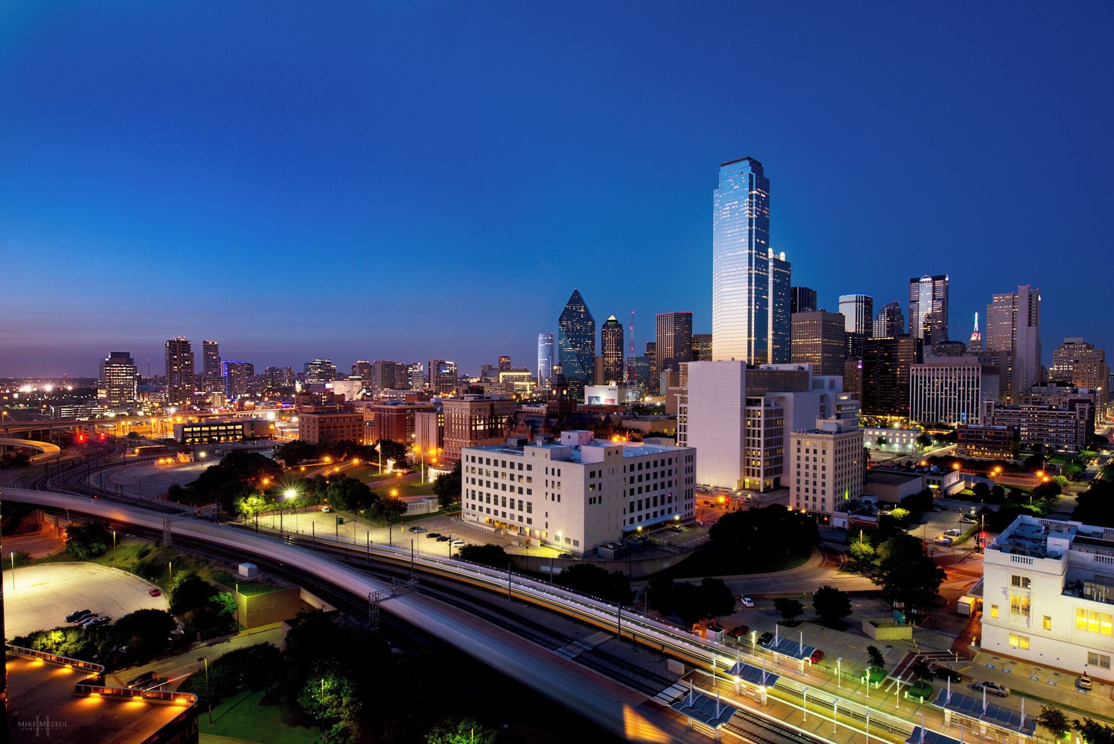 A city skyline with high-rise buildings, a highway, and a mix of urban and green spaces.