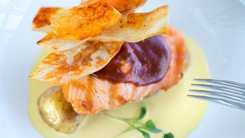 A plate with a piece of salmon, a slice of lemon, and a fork on a table.