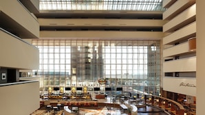 A spacious hotel atrium with multiple dining areas, an escalator, and a large glass facade allowing natural light. - Hyatt Regency Dallas (Dallas)