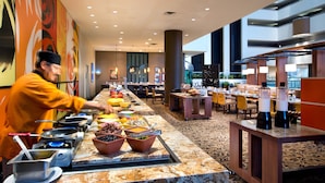 A buffet setup with various food items and cooking equipment.