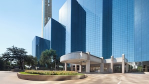 A modern hotel with a distinctive tower and reflective glass facade.