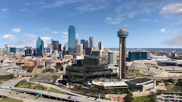 A city skyline with modern buildings, a prominent tower, and a highway with vehicles.