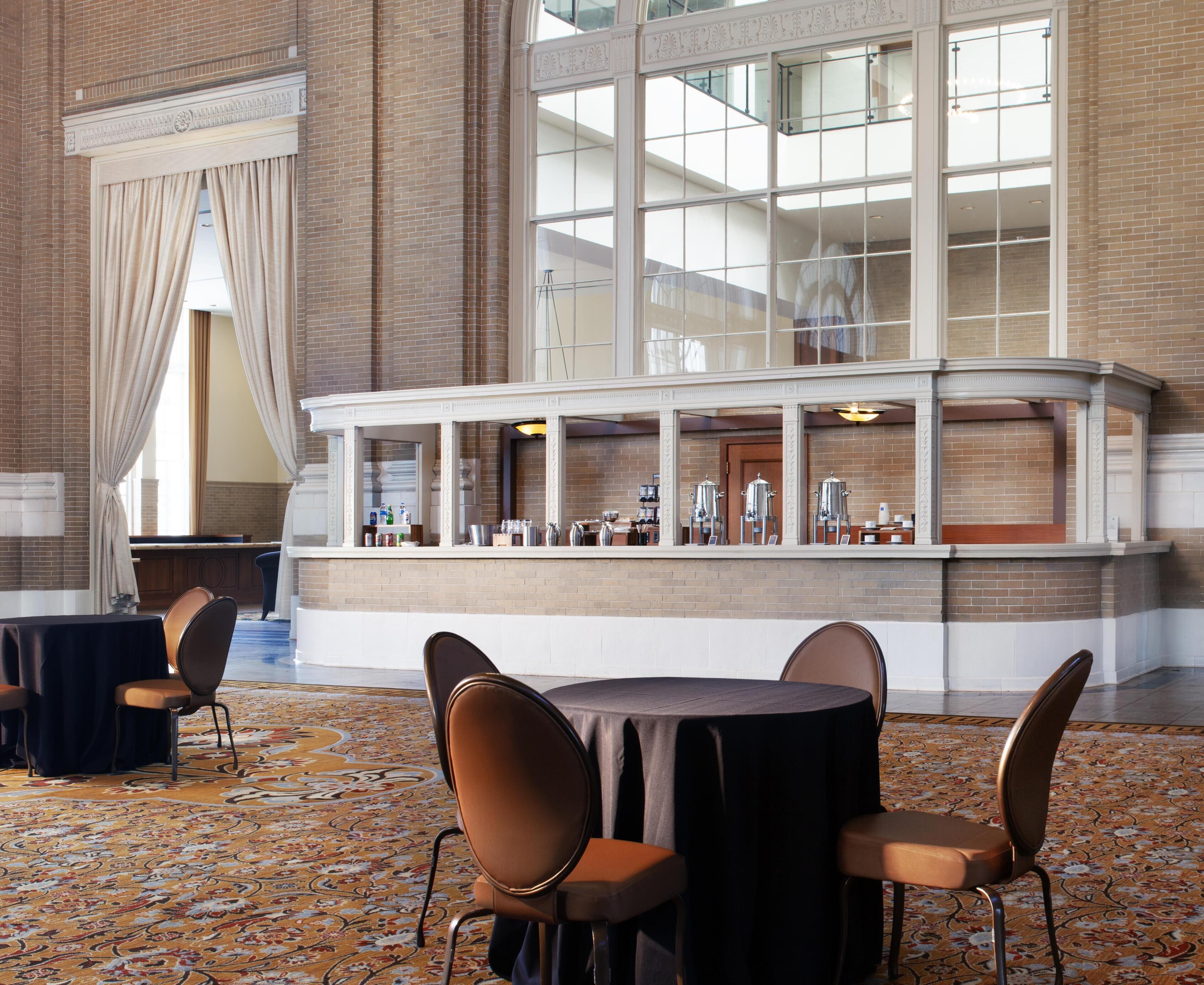 A hotel lobby with a bar area, seating arrangements, and a patterned carpet.