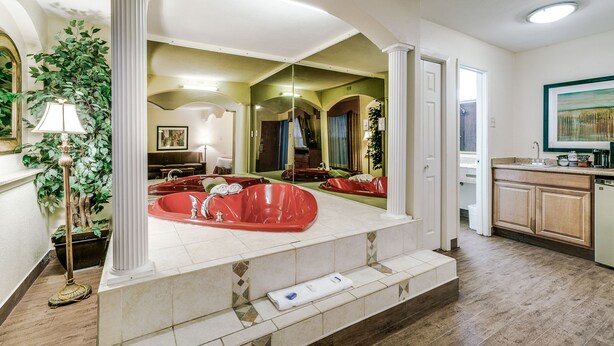 A spacious bathroom with a large bathtub, a mirror, and a potted plant. - Quality Inn & Suites Dallas - Cityplace (Dallas)