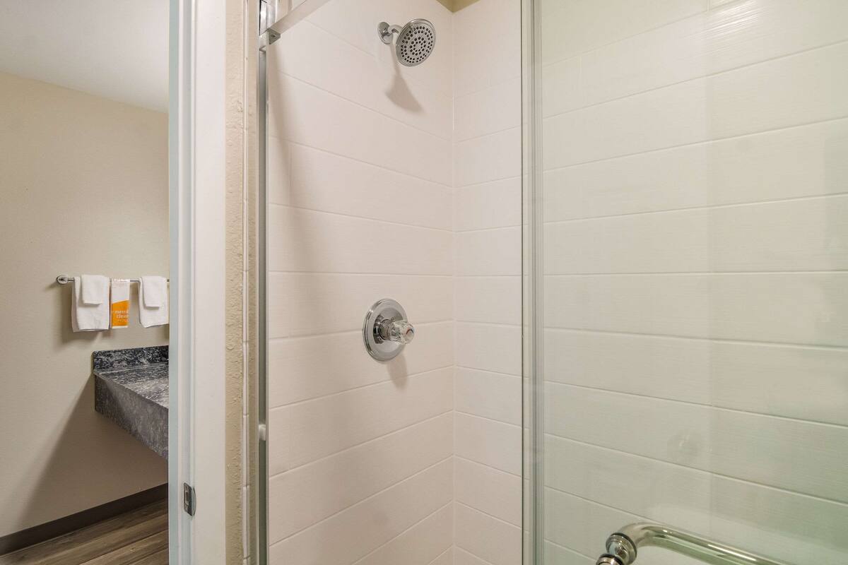 A shower with a glass door, a marble countertop, and a towel rack with towels.
