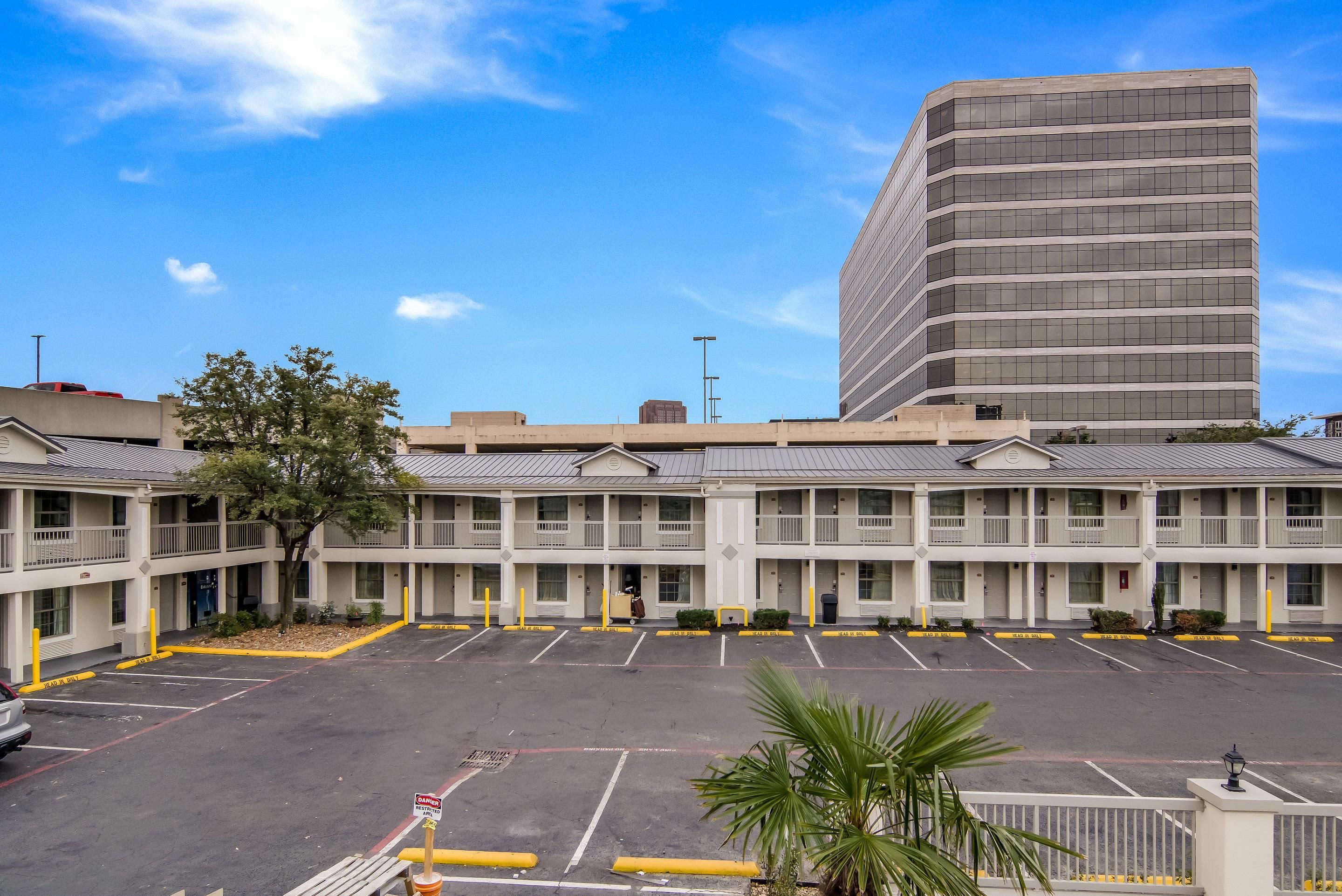 A multi-story motel with a parking lot in front.