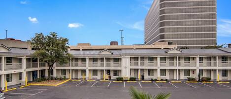 A multi-story motel with a parking lot in front.