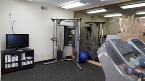 Un gimnasio con equipo de ejercicio, una televisión y un teléfono instalado en la pared.