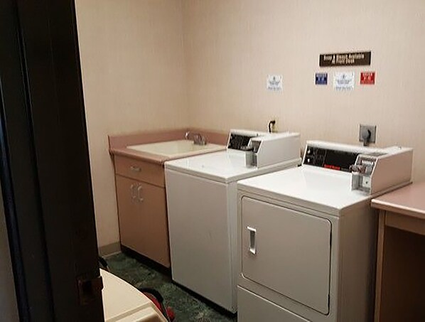 A laundry room with two washing machines and a sink.