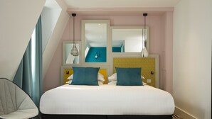 A modern bedroom with a large bed, two bedside tables, a chair, and a mirror. - Hôtel Haussmann Saint Augustin (Paris)