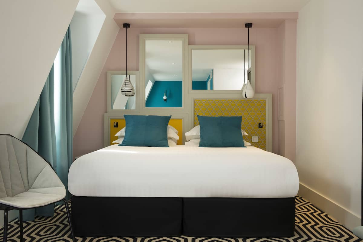 A modern bedroom with a large bed, two bedside tables, a chair, and a mirror.