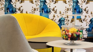 A yellow armchair, a glass candy dish, and a patterned wallpaper with blue lion statues. - Hôtel Haussmann Saint Augustin (Paris)