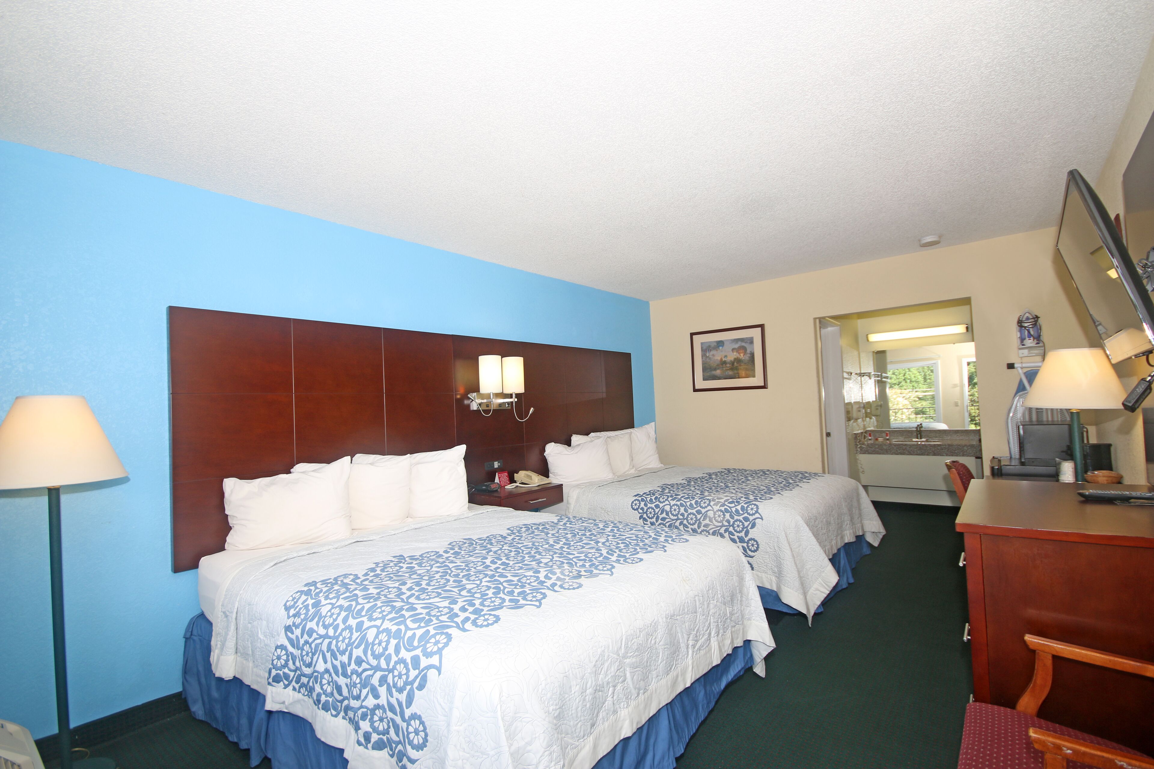 A hotel room with two beds, a desk, and a chair.