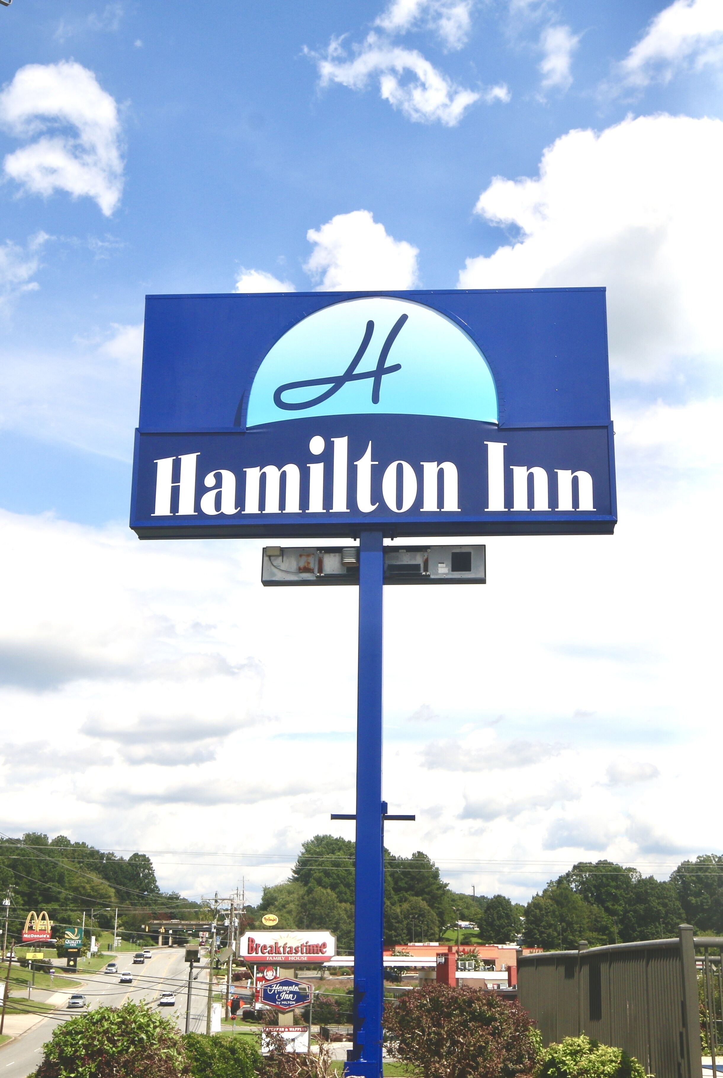 A blue sign for Hamilton Inn with a large 'H' logo.