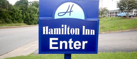 A blue sign with the text "Hamilton Inn Enter" and a stylized 'H' logo.