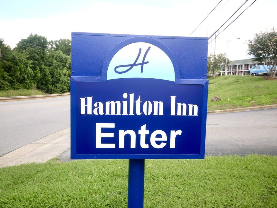 Un letrero azul con el texto 'Hamilton Inn Entrar' y un logo estilizado en forma de 'H'.