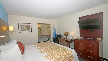 A hotel room with a bed, a desk, a dresser, a TV, and a painting on the wall.