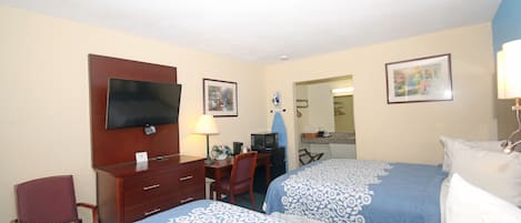 A hotel room with two beds, a desk, a chair, a TV, and a microwave.