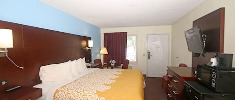 Habitación de hotel con una cama grande, un escritorio con silla, un televisor y un microondas.