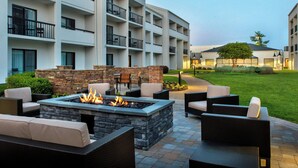 A courtyard with outdoor seating, a fire pit, and a building with multiple balconies. - Courtyard by Marriott Silver Spring North/White Oak (Silver Spring)