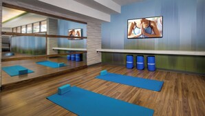 A modern fitness room with wooden flooring, blue exercise mats, and mirrored walls. - Courtyard by Marriott Silver Spring North/White Oak (Silver Spring)