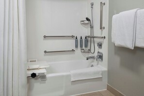 Un baño moderno con bañera, ducha e inodoro. Cuenta con barras de apoyo y un asidero para mayor seguridad.