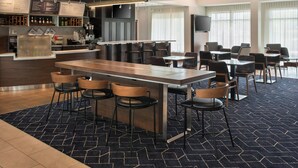 A modern hotel lobby with a bar area, seating arrangements, and a large screen. - Courtyard by Marriott Silver Spring North/White Oak (Silver Spring)