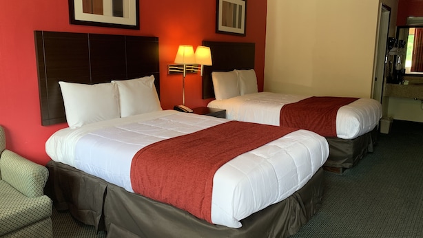 A hotel room with two beds, a desk, a chair, and a lamp. - Americas Best Value Inn Fredericksburg N (Fredericksburg)