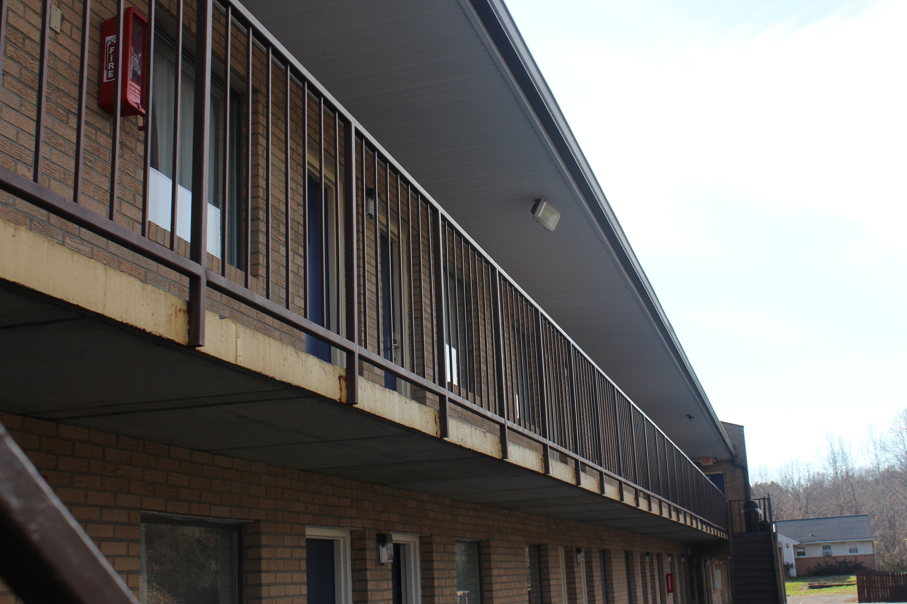 A building with a brick facade, a metal balcony railing, and a fire alarm box.