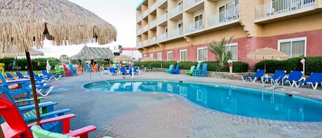 A hotel pool area with lounge chairs and umbrellas.