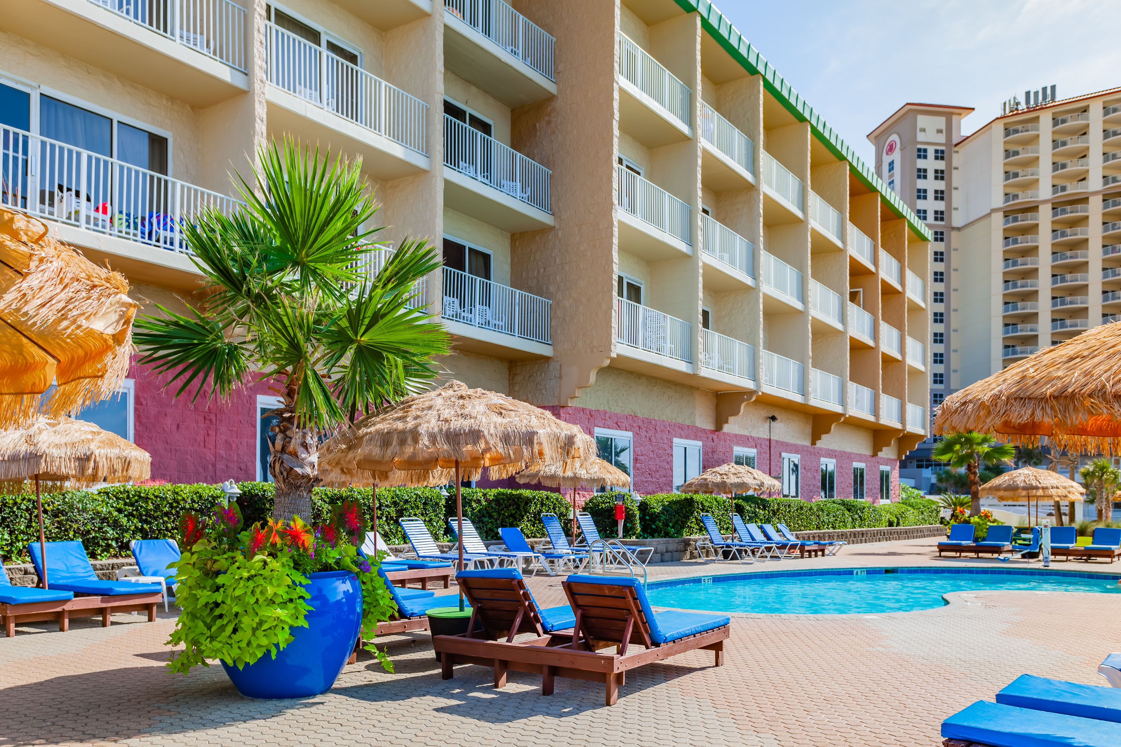 Ein Poolbereich eines Hotels mit Liegestühlen, Sonnenschirmen und einem großen Pool.