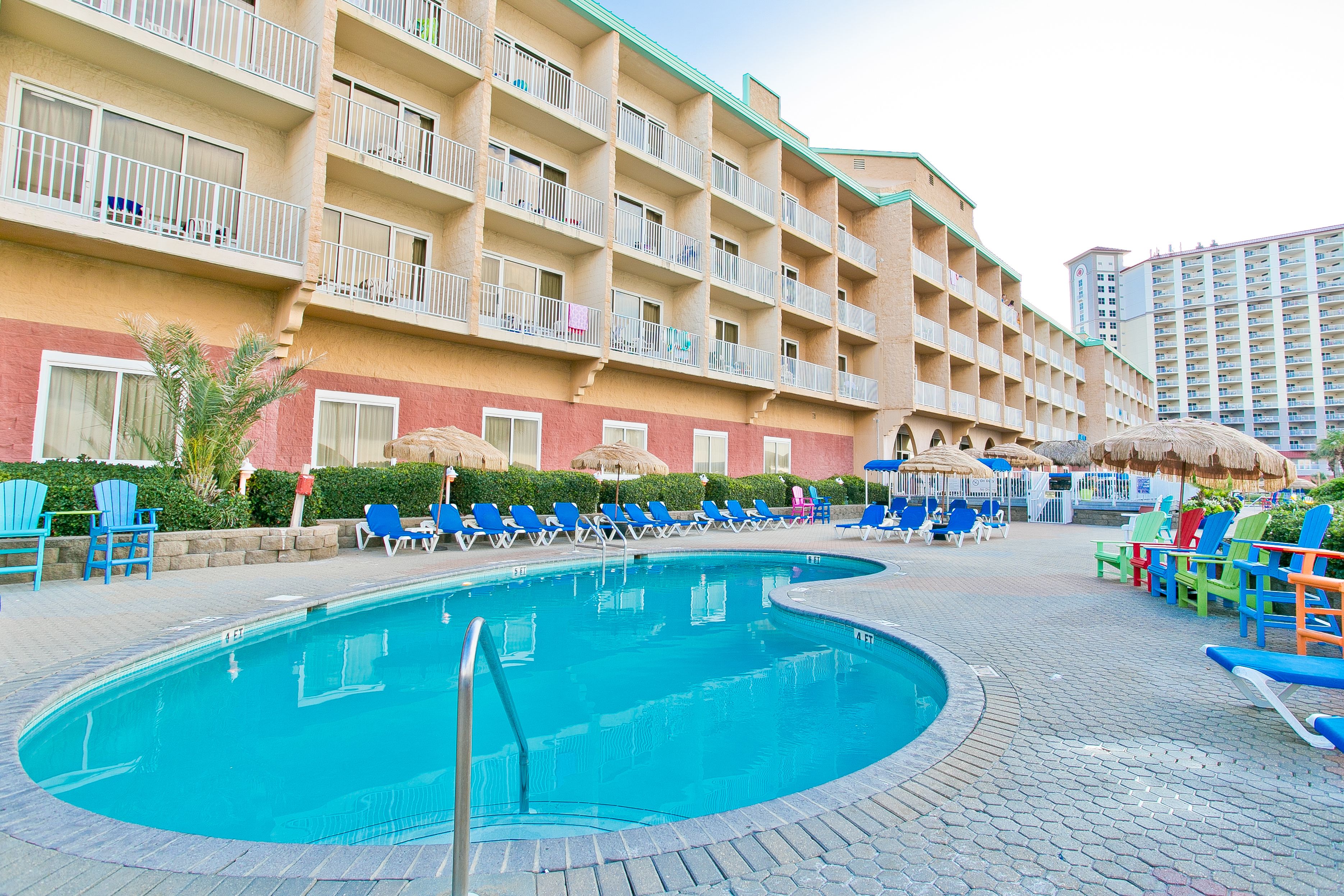 A hotel with a swimming pool, multiple balconies, and outdoor seating areas.