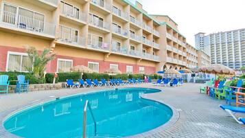 A hotel with a swimming pool, multiple balconies, and outdoor seating areas.
