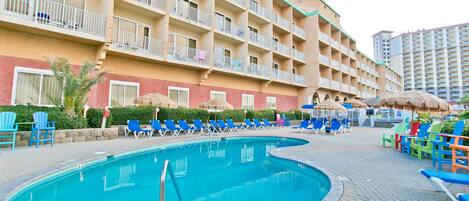A hotel with a swimming pool, multiple balconies, and outdoor seating areas.