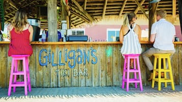 A wooden tiki bar with a sign reading "Gilligans Tiki Bar."