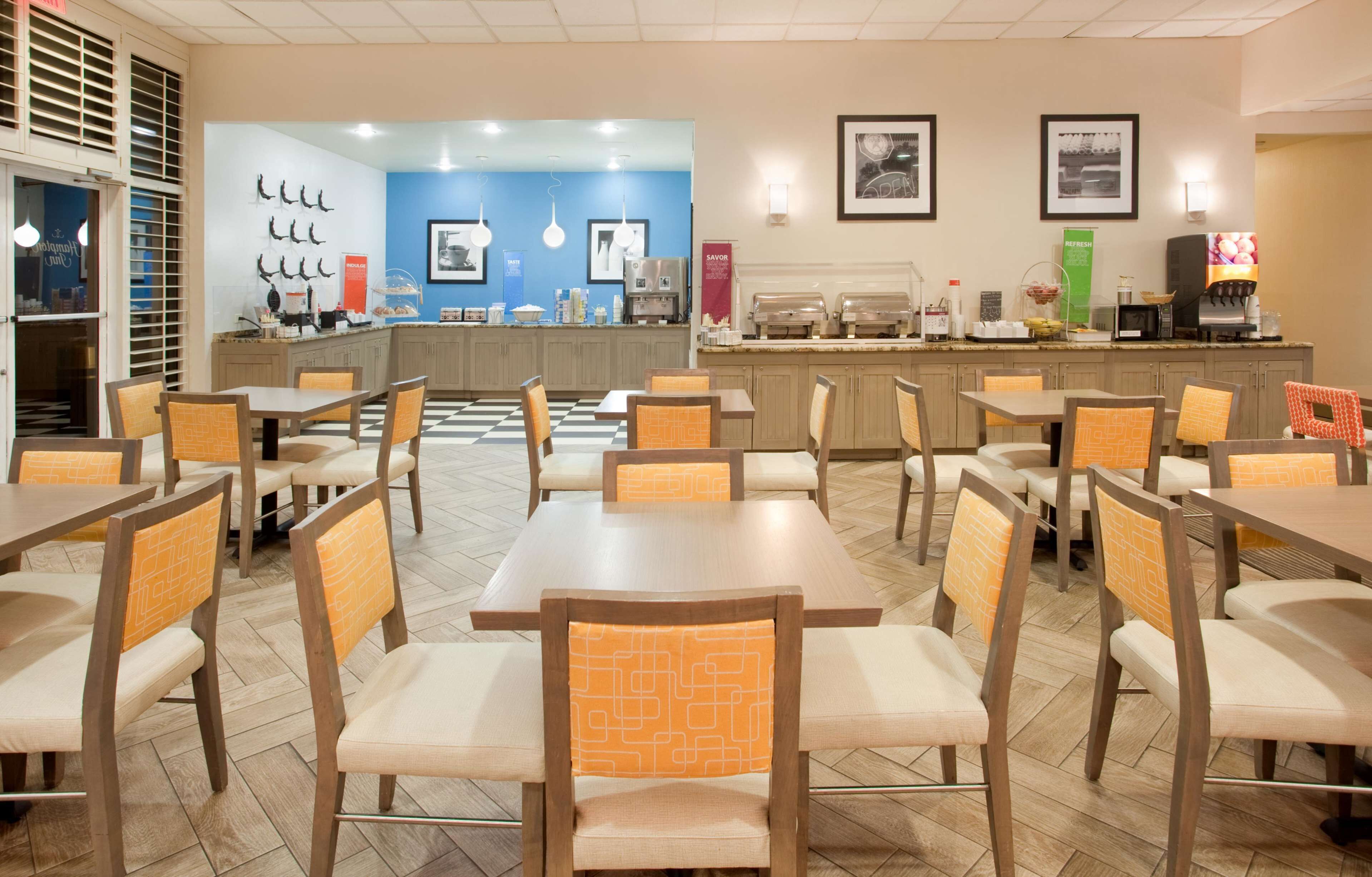 Un restaurante con mesas y sillas de madera, una barra con productos alimenticios y adornos en la pared.