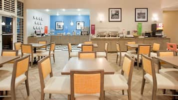 A restaurant with wooden tables and chairs, a counter with food items, and wall decorations.