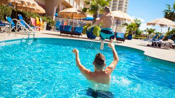 Relax by the clear pool surrounded by lounge chairs and umbrellas.