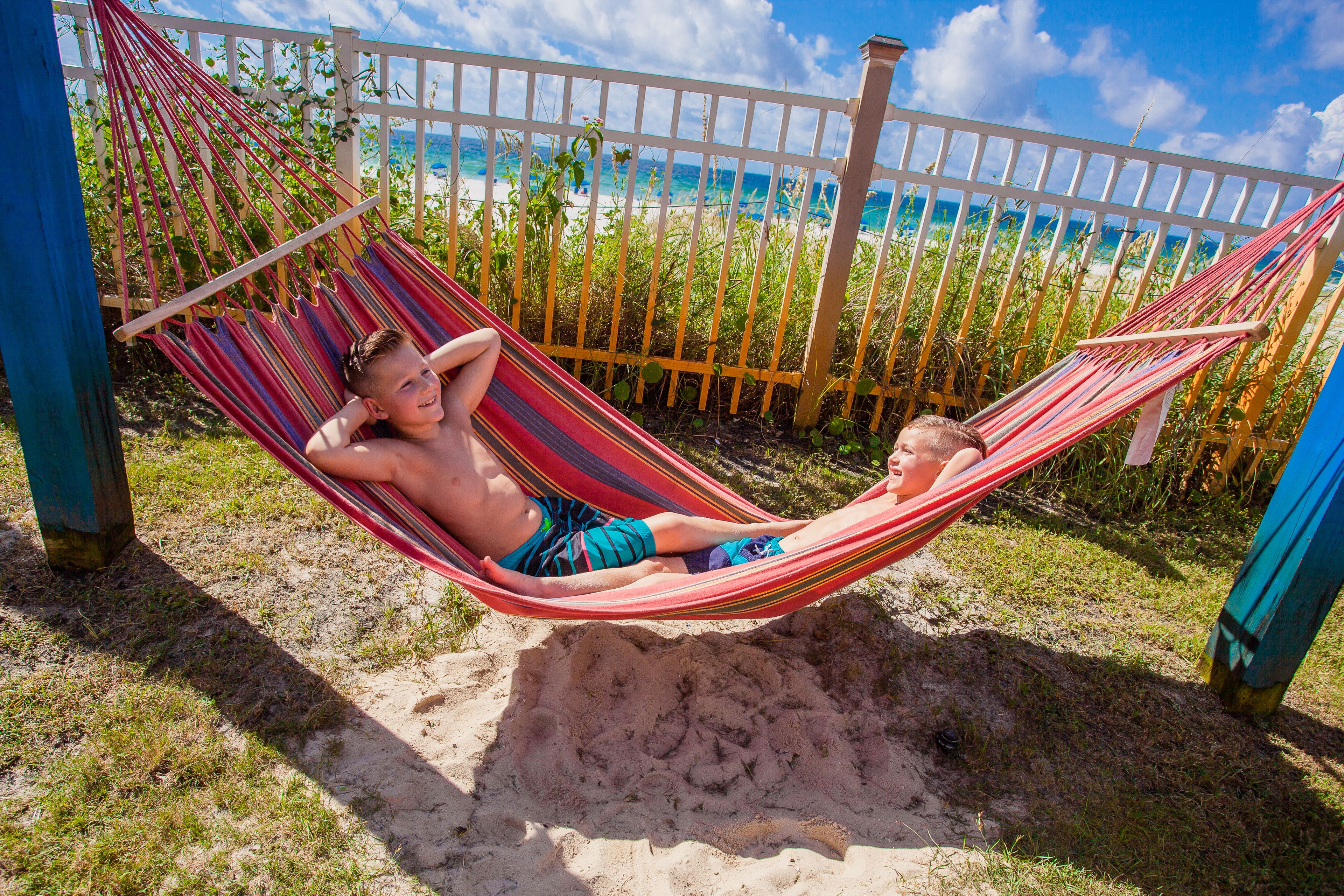 A hammock in a sandy area with a view of the beach and ocean.