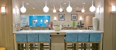 A modern kitchen with a central island, bar stools, pendant lighting, and a blue accent wall.