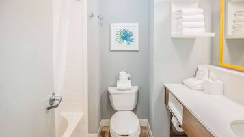 Un baño con inodoro, lavabo, espejo y ducha.
