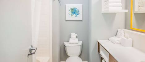 Un baño con inodoro, lavabo, espejo y ducha.