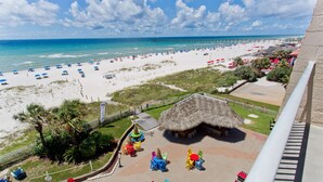 A beach resort with a thatched-roof hut, colorful chairs, and umbrellas. - Hampton Inn Pensacola Beach (Pensacola Beach)