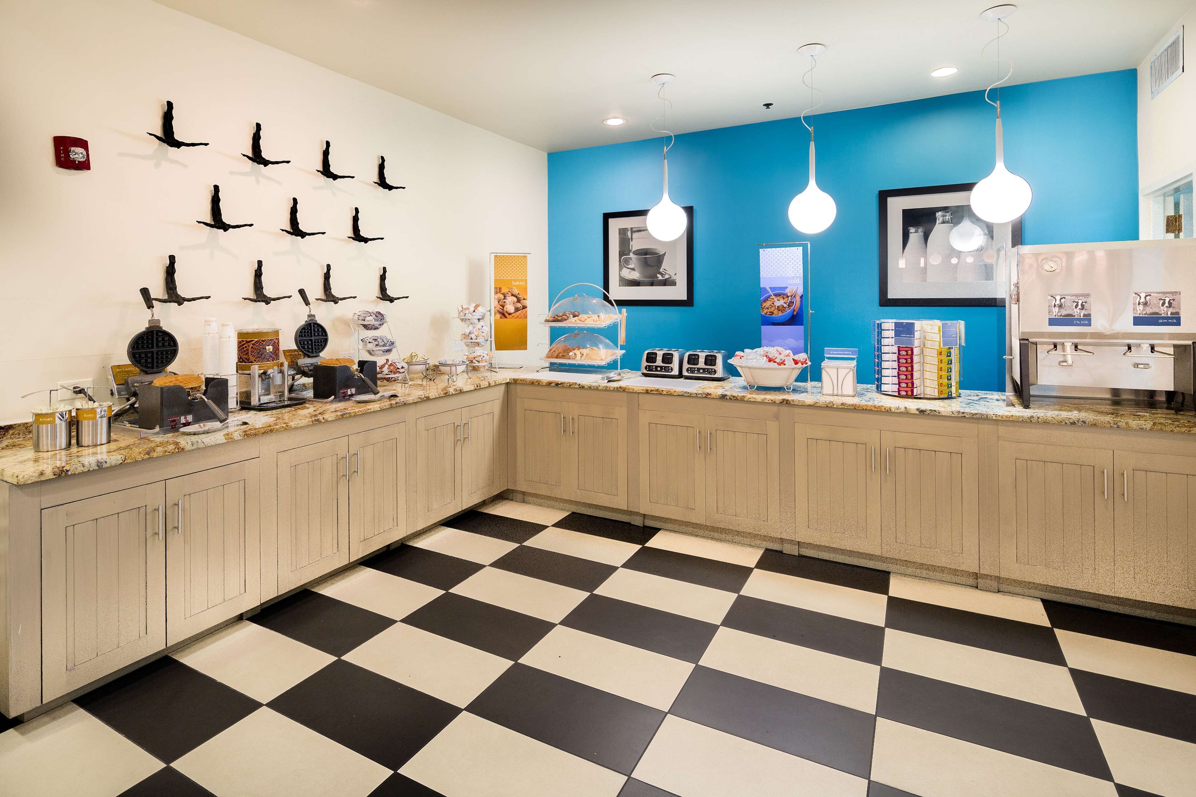 A kitchen with a checkered floor, a blue accent wall, and various appliances and utensils on the counter.