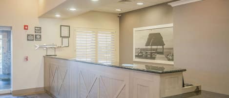 A reception area with a counter, a framed picture on the wall, and a door with a glass panel.