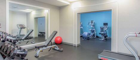 A gym with various exercise equipment, including dumbbells, a treadmill, and exercise balls.