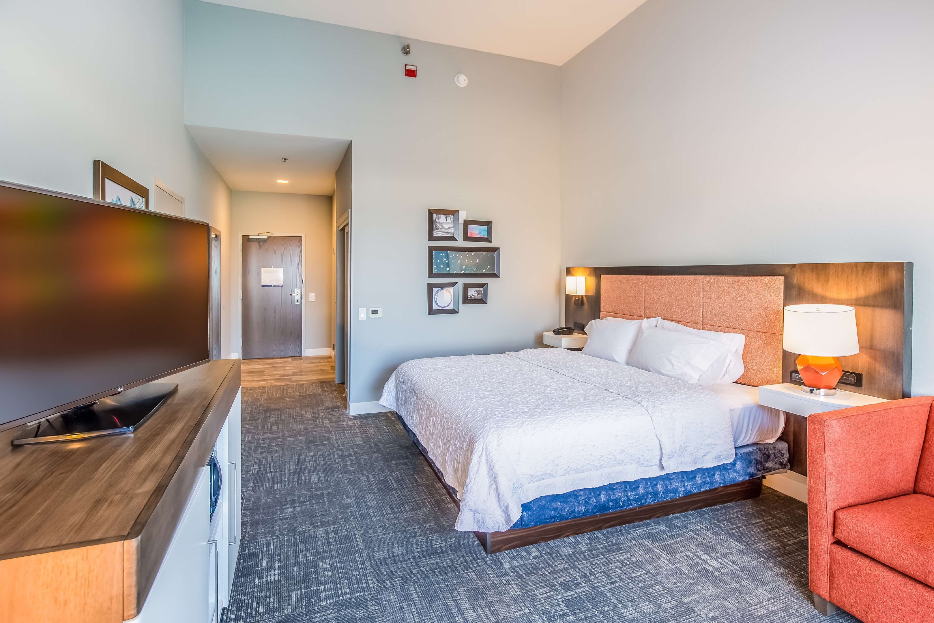 Una habitación de hotel con cama, televisión, escritorio y silla.