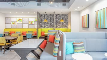 Un comedor moderno con una mesa larga, diversas opciones de asientos y una decoración colorida y con estampados.