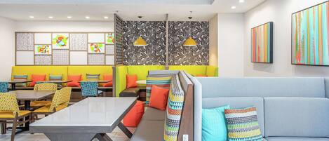A modern dining area with a long table, multiple seating options, and a mix of colorful and patterned decor.