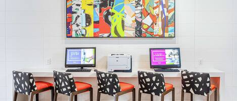 A reception area with a large abstract painting, two computers, and four patterned chairs.